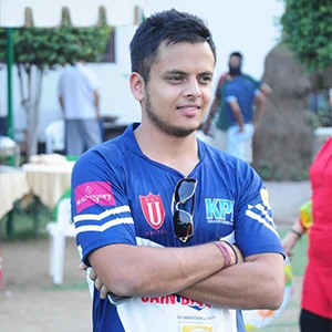 Arjun Gupta cricketer standing with arms crossed in blue cricket jersey at ground